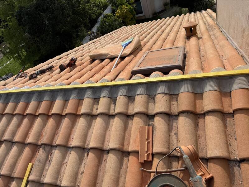 Réparation de toiture en cours sur des tuiles